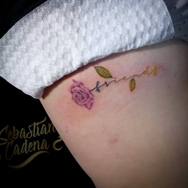 Rosa a color con la palabra friends en fine line sobre las costillas